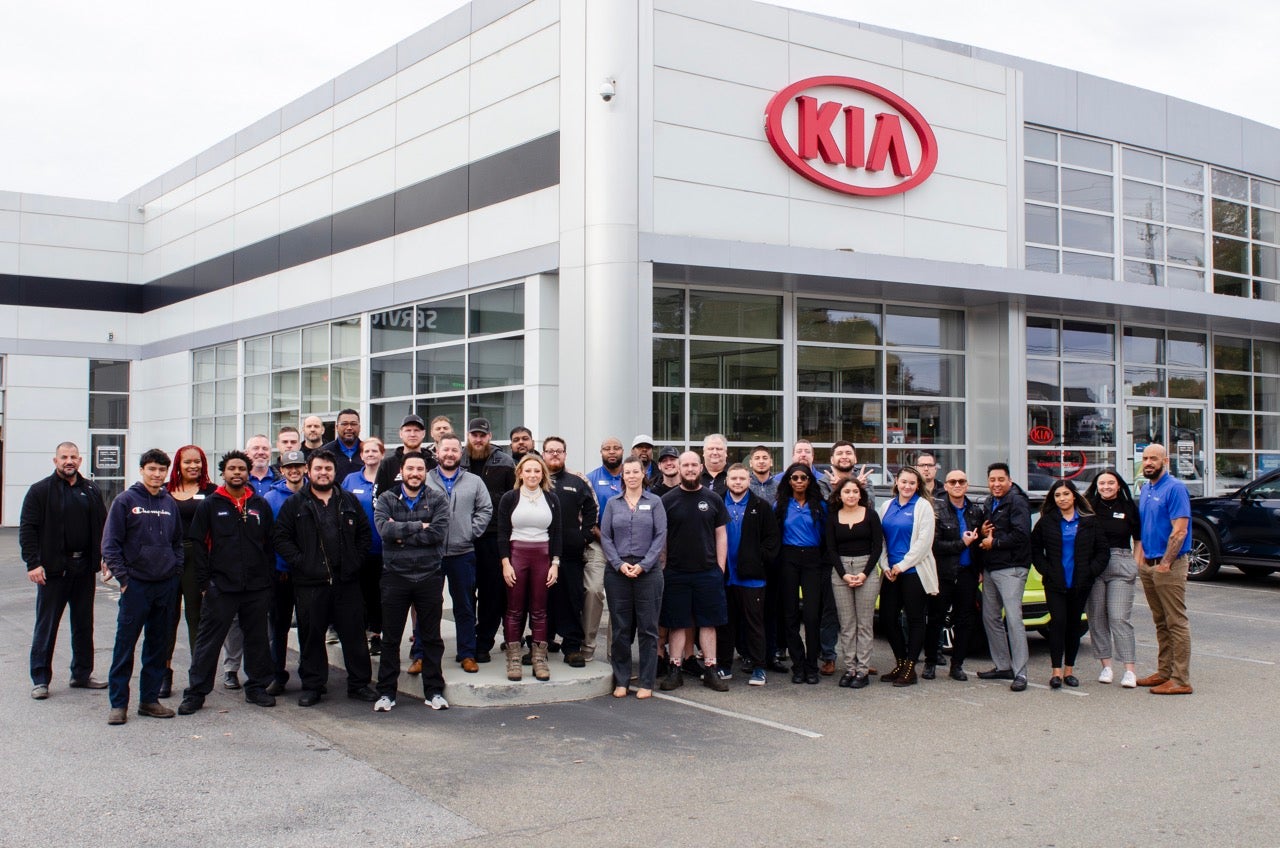 Jim Shorkey Gainesville Kia team smiling in front of their Gainesville-area Kia dealership